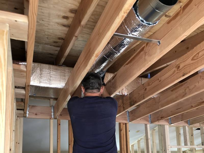 Our tech hanging new insulated duct in a home renovation